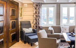 A living room with a wooden door, a grey armchair, a beige sofa, and a view of a marina through large windows. - Cozy home in Jelsa with house sea view (Jelsa)