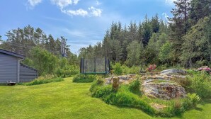 Ein gepflegter Garten mit Rasenfläche, einer Schaukel und einem Haus im Hintergrund.