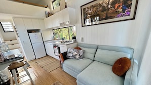 Een gezellig compact verblijf met een kitchenette, een bank met kussens en een eethoek.