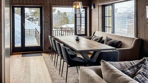 A wooden interior with a dining table, chairs, a bench, and large windows offering a view of a snowy landscape. - Lovely home in Bjorli with sauna (Bjorli)