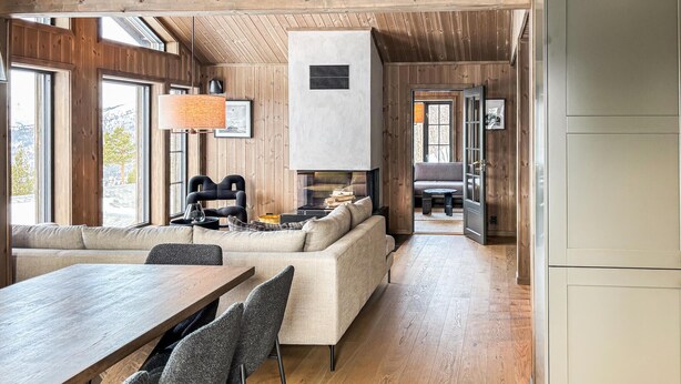 A cozy cabin interior with a wooden dining table, a sofa, and a fireplace. - Lovely home in Bjorli with sauna (Bjorli)