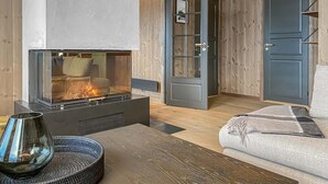 A cozy room with a fireplace, a sofa, and a door leading to another space. - Lovely home in Bjorli with sauna (Bjorli)