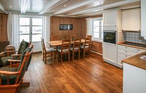 A cozy kitchen with wooden flooring, a dining table with chairs, and a built-in oven.