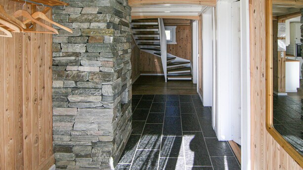 Ein Korridor mit Steinwand, Holzboden und einer Wendeltreppe.