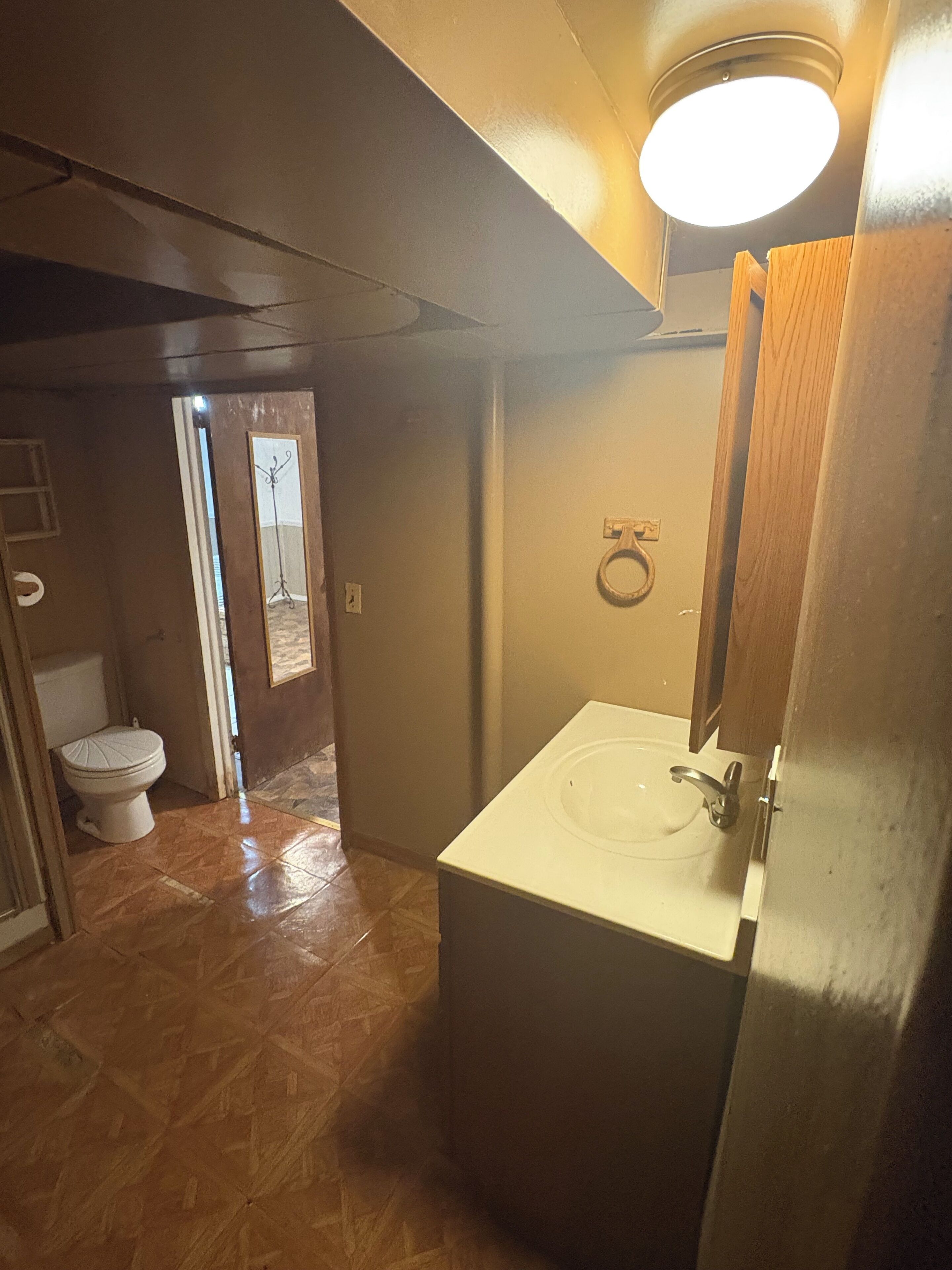 A bathroom with a white sink, a wooden door, and a tiled floor.