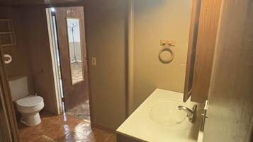 A bathroom with a white sink, a wooden door, and a tiled floor.