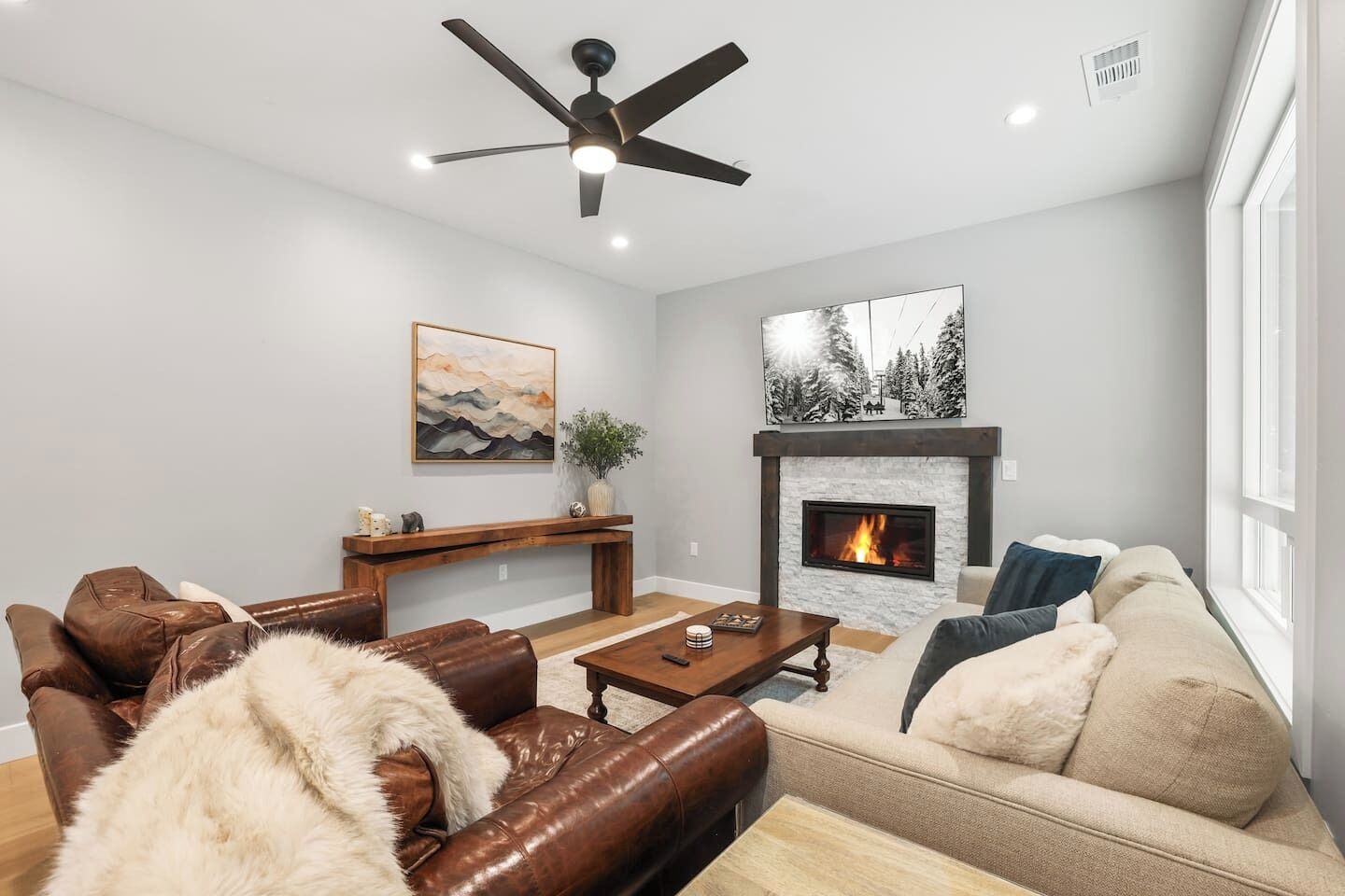 Un salón con chimenea, muebles de cuero y ventilador de techo.