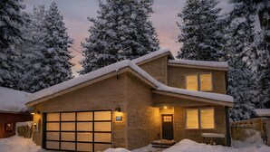 Ein zweistöckiges Haus mit Garage, umgeben von schneebedeckten Bäumen.