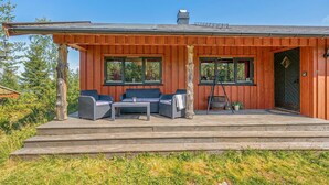 A wooden cabin with a porch, outdoor seating, and a view of the ocean.
