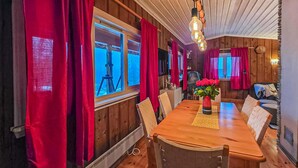 A dining area with a wooden table, red curtains, and a vase of flowers.