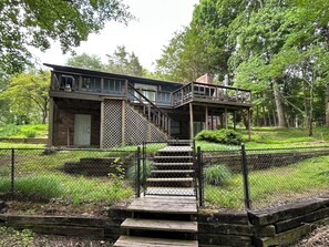 A wooden cabin with a balcony, a staircase leading to the entrance, and a fenced garden area. - Private 3 Bed/2 Bath Watts Bar Lakehouse on Fenced 2 Acres [newly listed 2026] (Ten Mile)