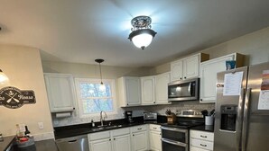 Una cocina moderna con armarios blancos, un refrigerador de acero inoxidable, un microondas y un horno empotrado.