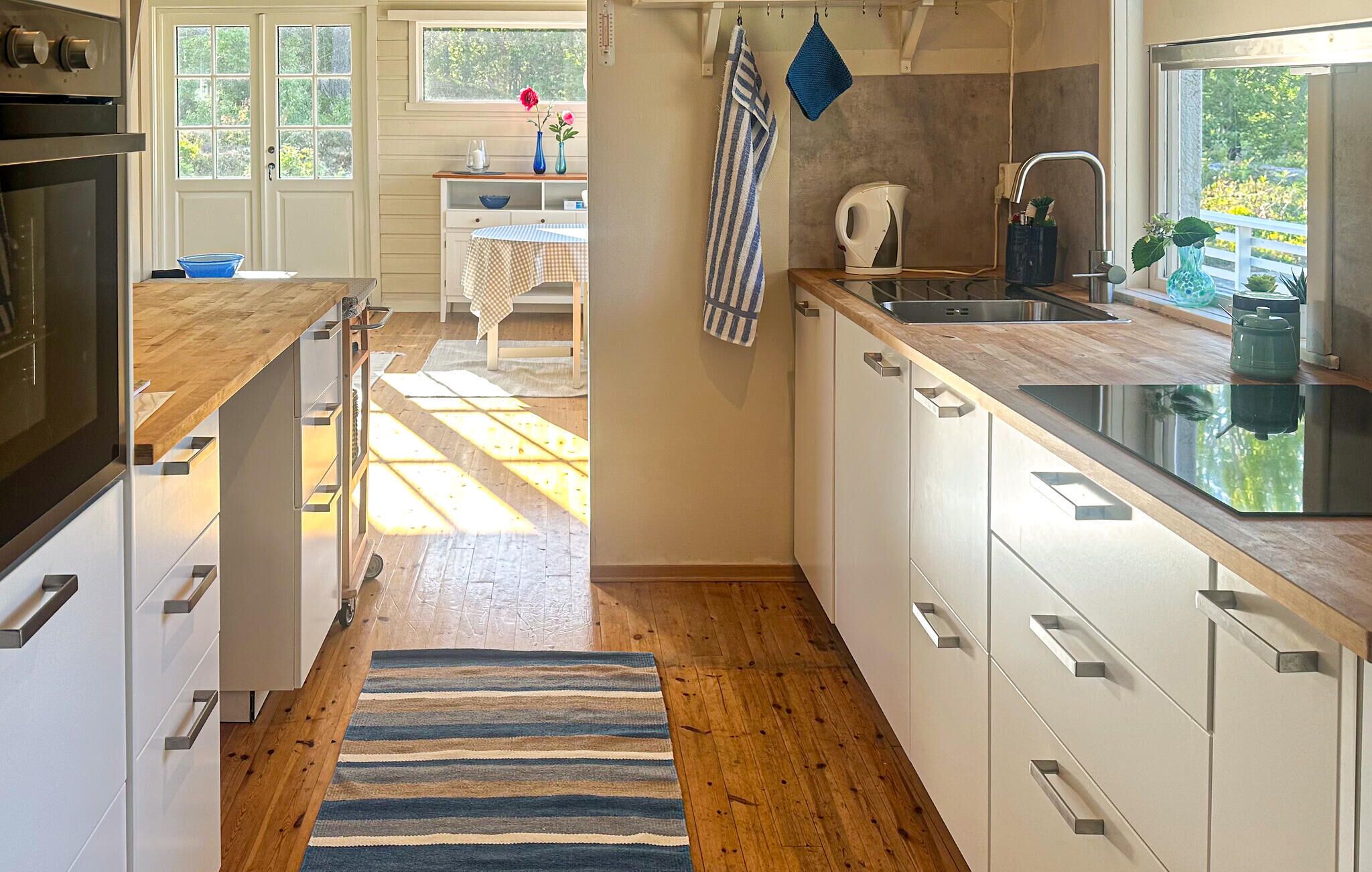 A modern kitchen with wooden countertops, a built-in dishwasher, and a window overlooking a garden.