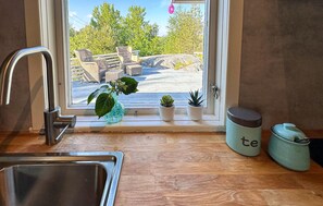 A kitchen with a sink, a window with potted plants, and a view of outdoor furniture. - 2 bedroom cozy home in Brekkestø (Brekkestø)