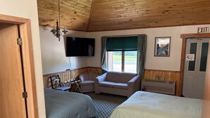 Una habitación con dos camas, televisión, una silla, señal de salida y ventana con cortinas.