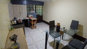 Una cocina compacta con comedor, que incluye una pequeña mesa, sillas y un taburete.
