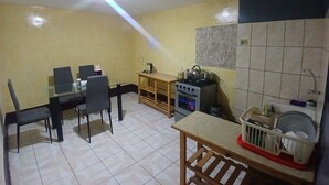 Een kleine keuken met een eethoek, een fornuis en een spoelbak.