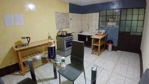 Una pequeña cocina con estufa, lavabo y comedor con sillas y mesa.