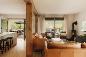 Een ruime woonkamer met een leren bank, een eettafel met stoelen, een keuken en een open haard.