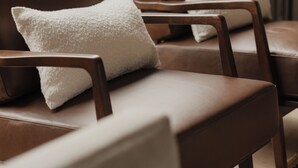Une pièce comprenant deux fauteuils en cuir, chacun agrémenté d’un coussin blanc, placés près d’une fenêtre donnant sur un balcon.