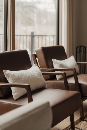 Una habitación con dos sillones de cuero, cada uno con un cojín blanco, ubicados cerca de una ventana con vistas a un balcón.