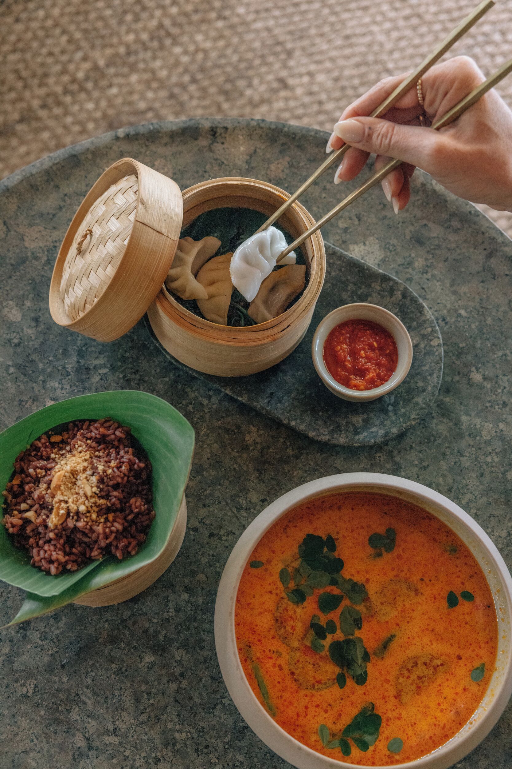 Una mesa con un tazón de sopa, un tazón de arroz y un tazón pequeño de salsa.