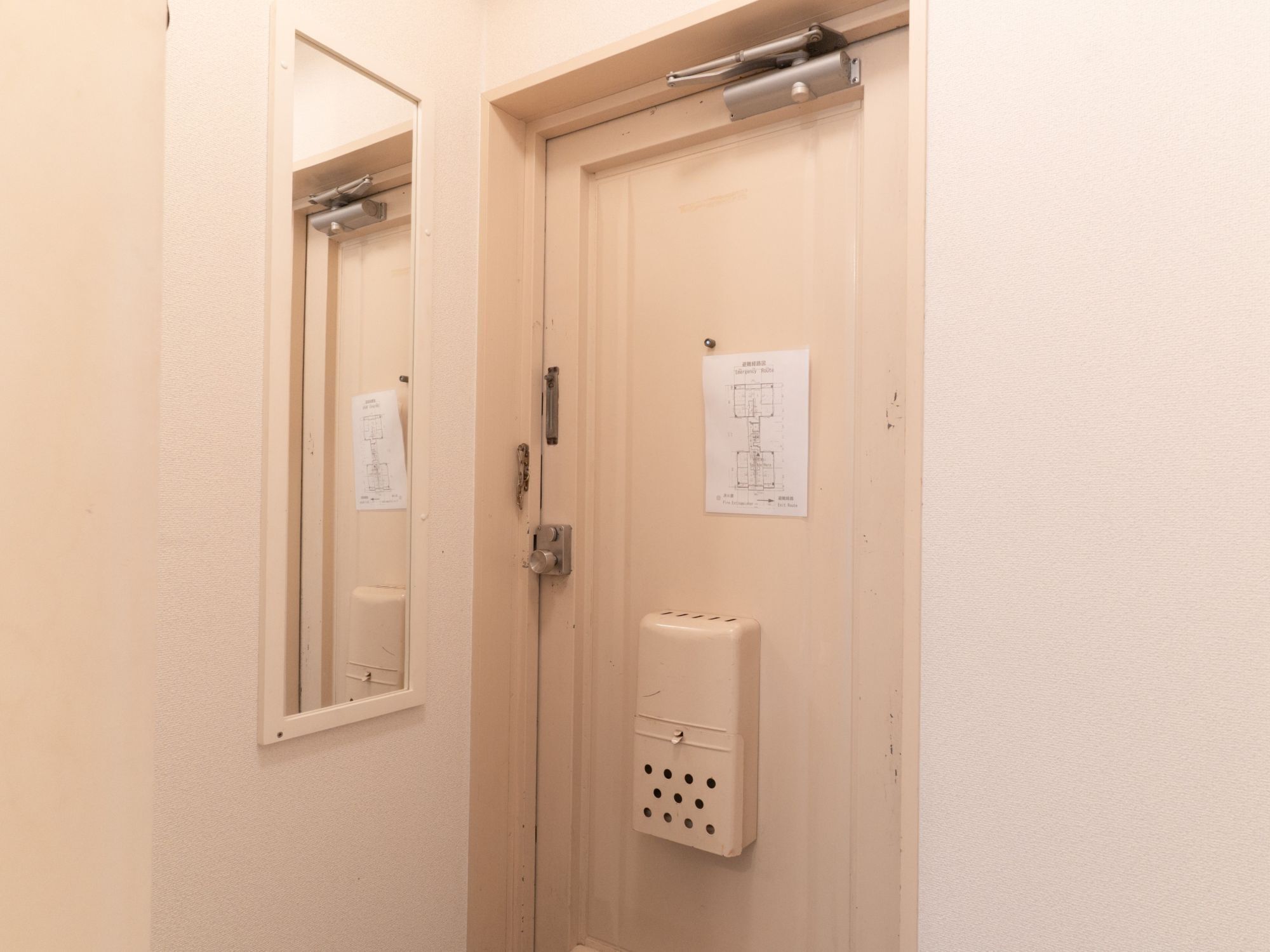 A door with a mirror, a doorbell, and a wall-mounted electrical box.