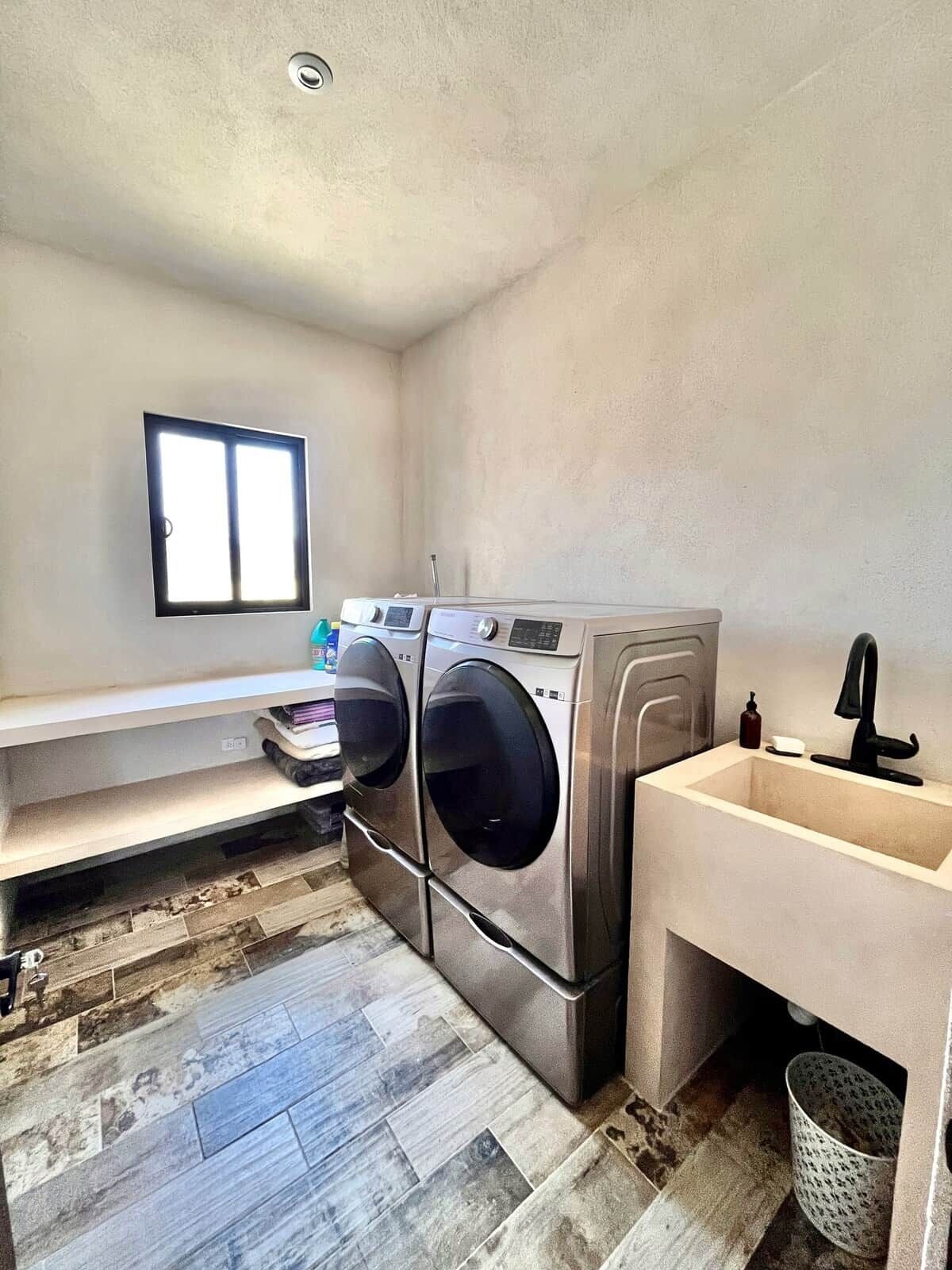 A laundry room with two stacked front-loading washers and a sink.
