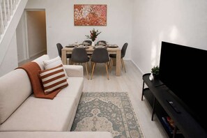 Un soggiorno moderno con un divano, un tavolo da pranzo per quattro persone e una televisione a schermo piatto su un mobile.