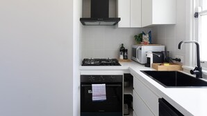 Una cucina moderna con mobili bianchi, un piano cottura nero, un forno a microonde e un lavello.