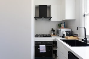 Una cocina moderna con armarios blancos, una estufa negra, un microondas y un lavamanos.