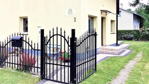 A gated entrance to a building with a mailbox, a small garden with red flowers, and a pathway leading to the entrance. - 1 bedroom amazing apartment in Rowy (Rowy)
