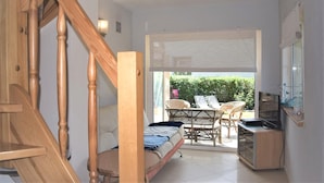 A compact room with a bed, a TV, a small table, and a chair. There is a window with a view of greenery outside. - 1 bedroom amazing apartment in Rowy (Rowy)