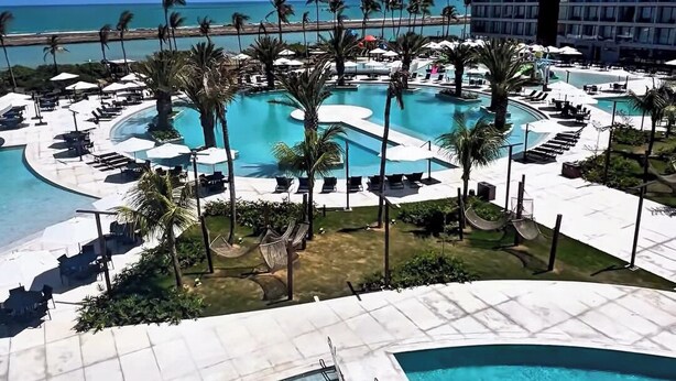 A resort with multiple swimming pools, palm trees, and a view of the ocean. - Porto 2 Life Resort (Ipojuca)