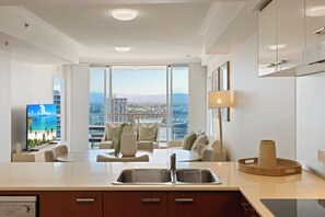 Eine moderne Küche mit einer großen Kochinsel, einer integrierten Spüle und Blick auf die Stadt durch große Fenster.