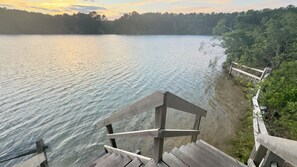 Um deck de madeira com vista para um lago calmo e uma margem coberta por floresta.