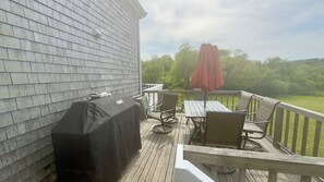 A deck with a grill, chairs, and a table. - 1800 Farmhouse · 6 Suites · Pets · Guest Cottage (Provincetown)
