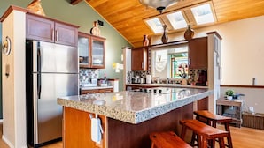 Una cocina con una isla grande, armarios de madera y un refrigerador de acero inoxidable.