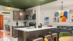 Eine moderne Küche mit einer zentralen Kochinsel, Barhocker und einem Essbereich mit Tisch und Stühlen.