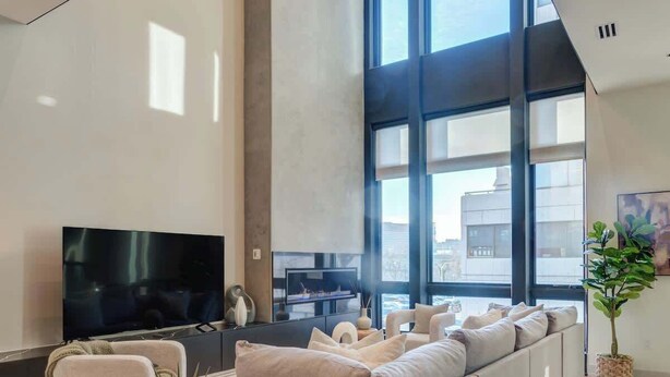 Een moderne woonkamer met een grote bank, een flatscreen televisie en een open haard.