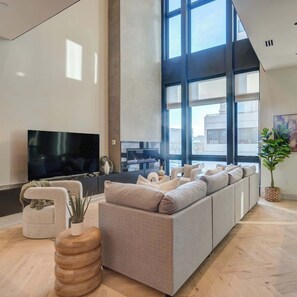 Un salon moderne avec un grand canapé, un téléviseur à écran plat et une cheminée.