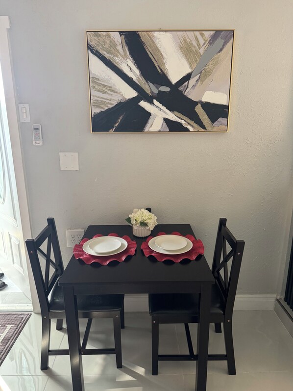 Une table à manger avec deux chaises, un vase de fleurs et un tableau accroché au mur.