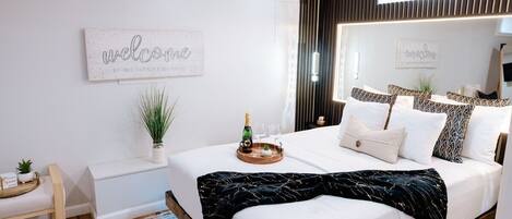 Een verzorgde hotelkamer met een groot bed, een nachtkastje, een klein zithoekje en een wandairconditioner.