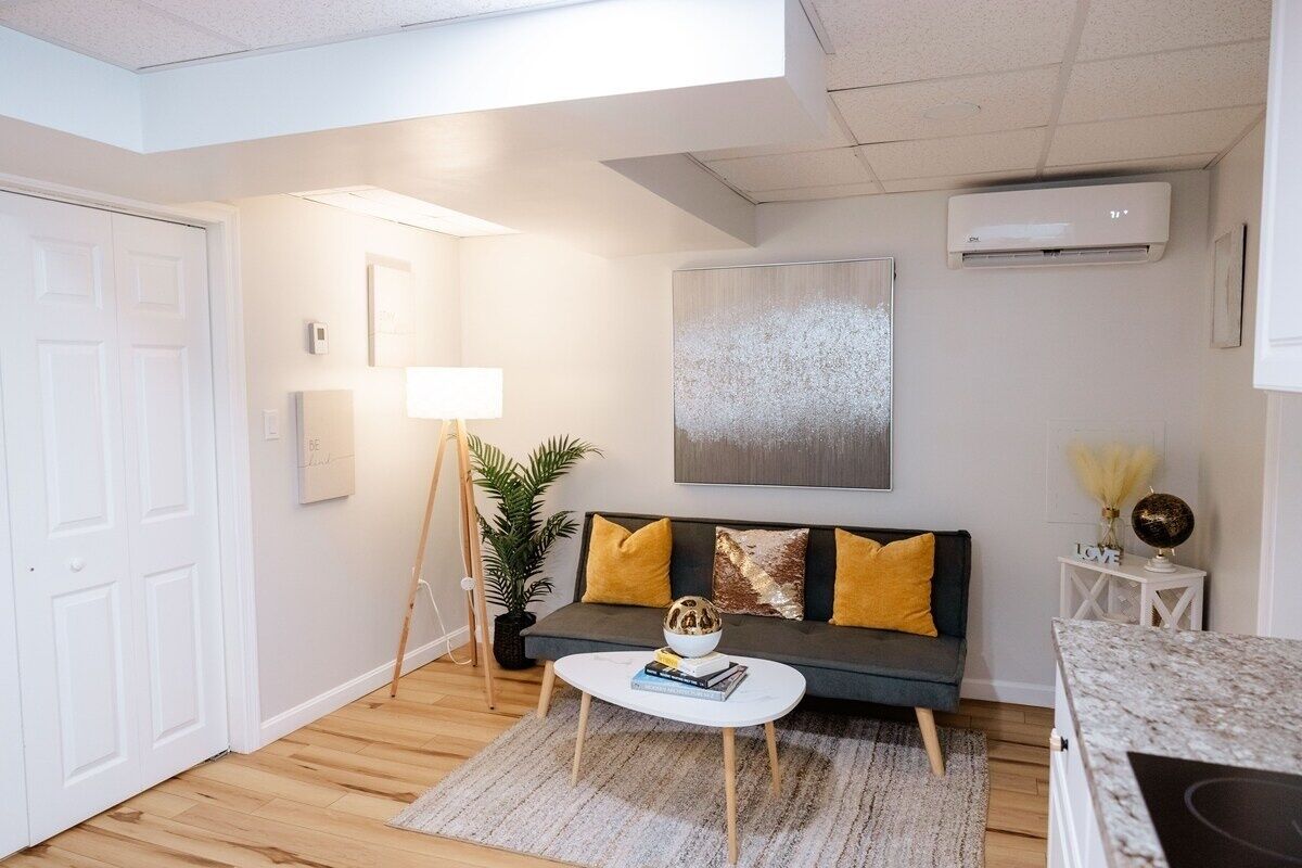 A modern living room with a dark grey sofa, a white coffee table, and a large abstract painting on the wall.