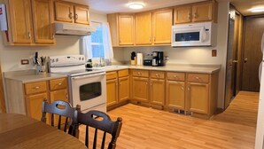 Una cocina con armarios de madera, estufa, microondas y cafetera.