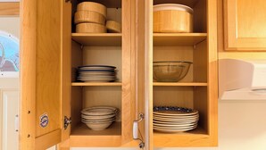 Un armario de madera con varios estantes, algunos con platos y cuencos apilados.