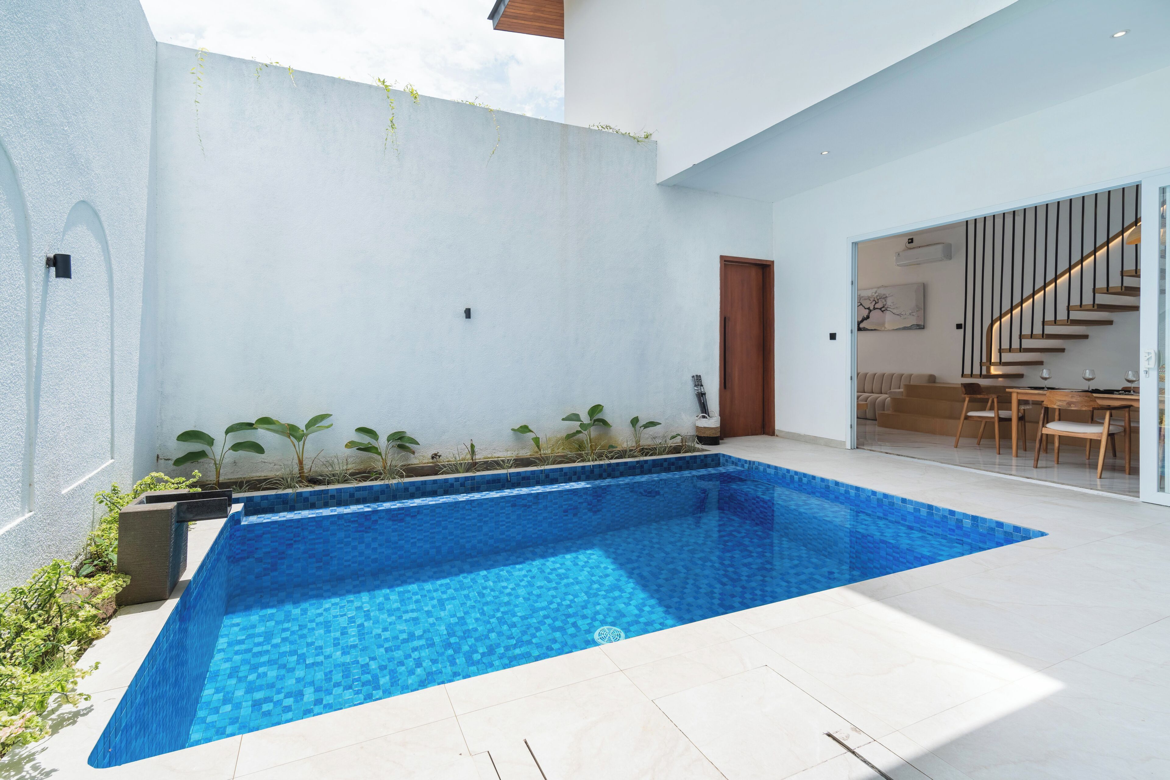 A modern indoor swimming pool with a tiled floor and a clear blue pool.
