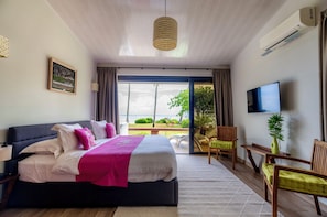 Ein Schlafzimmer mit Bett, Fernseher, Pflanze und Blick ins Freie.