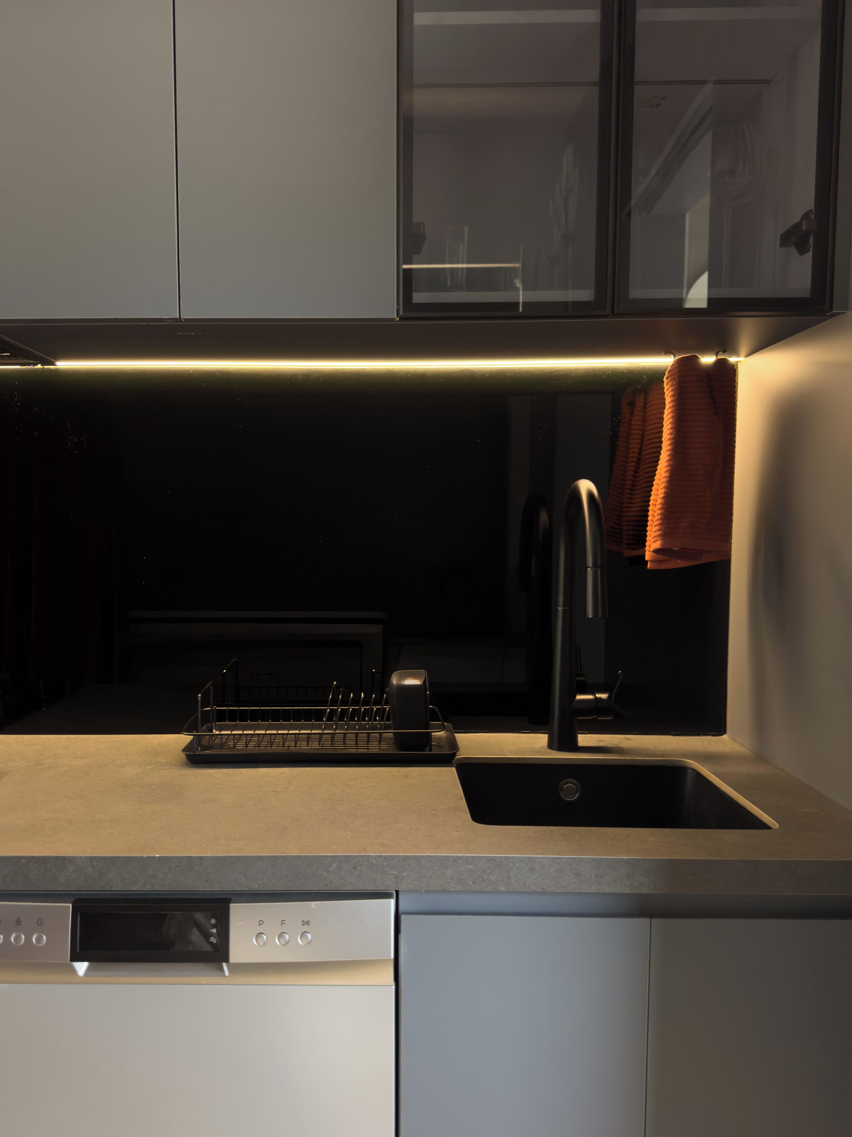 A modern kitchen with a dishwasher, a sink, and a stainless steel faucet.