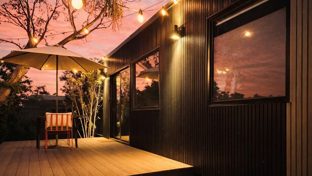 Una terraza al aire libre con piso de madera, una silla y luces colgantes.